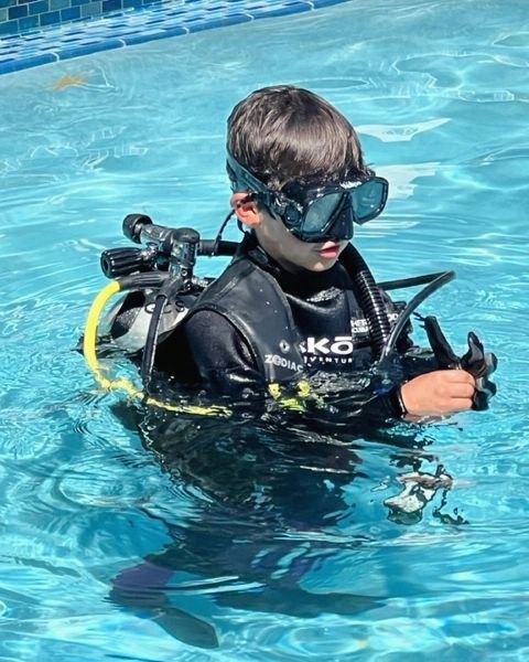 Young boy practicing scuba skills in the pool